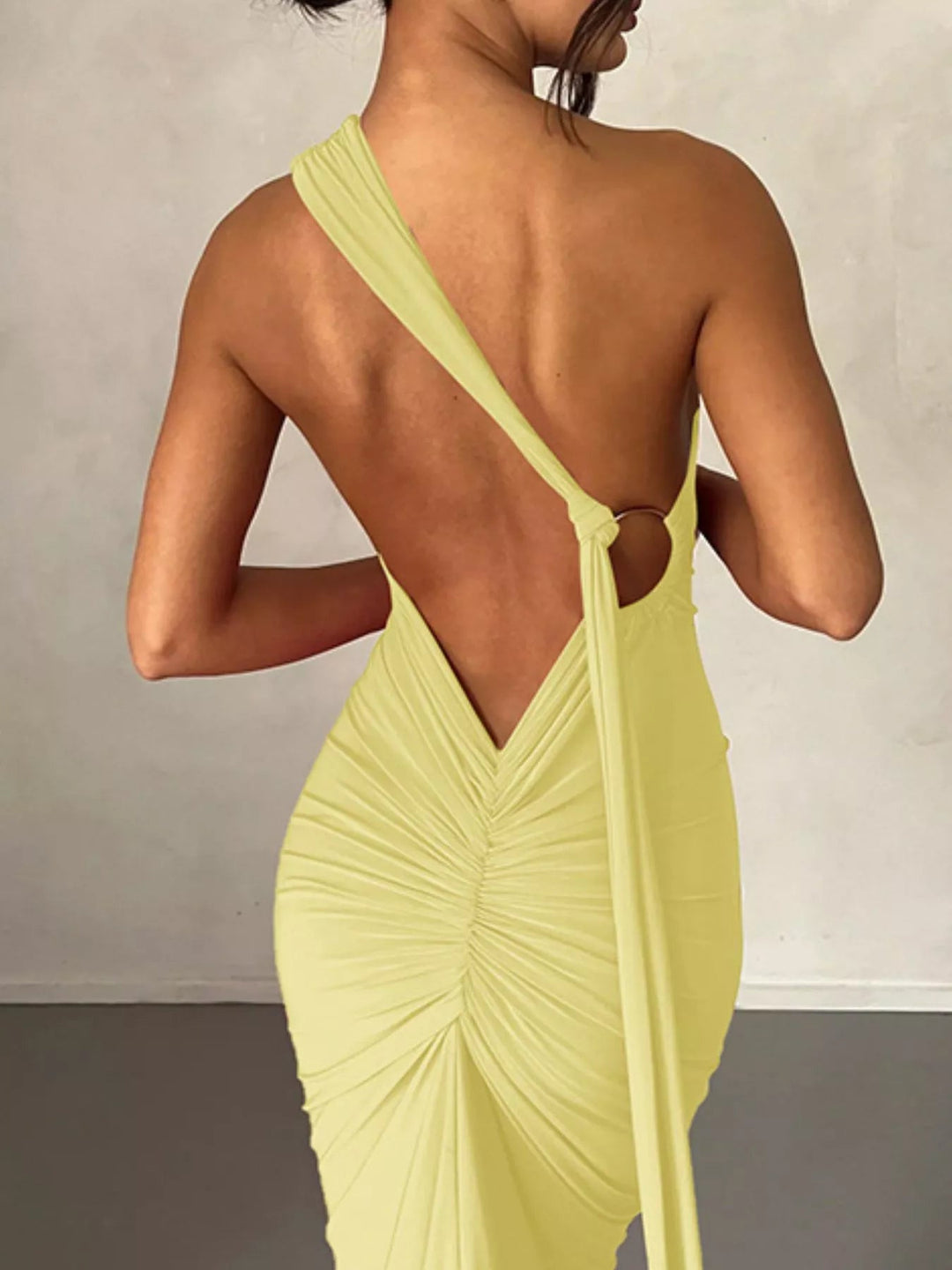 Backless One-Shoulder Bodycon Dress with ruched detailing, asymmetrical neckline, open back design, and elegant floor-length fitted silhouette.