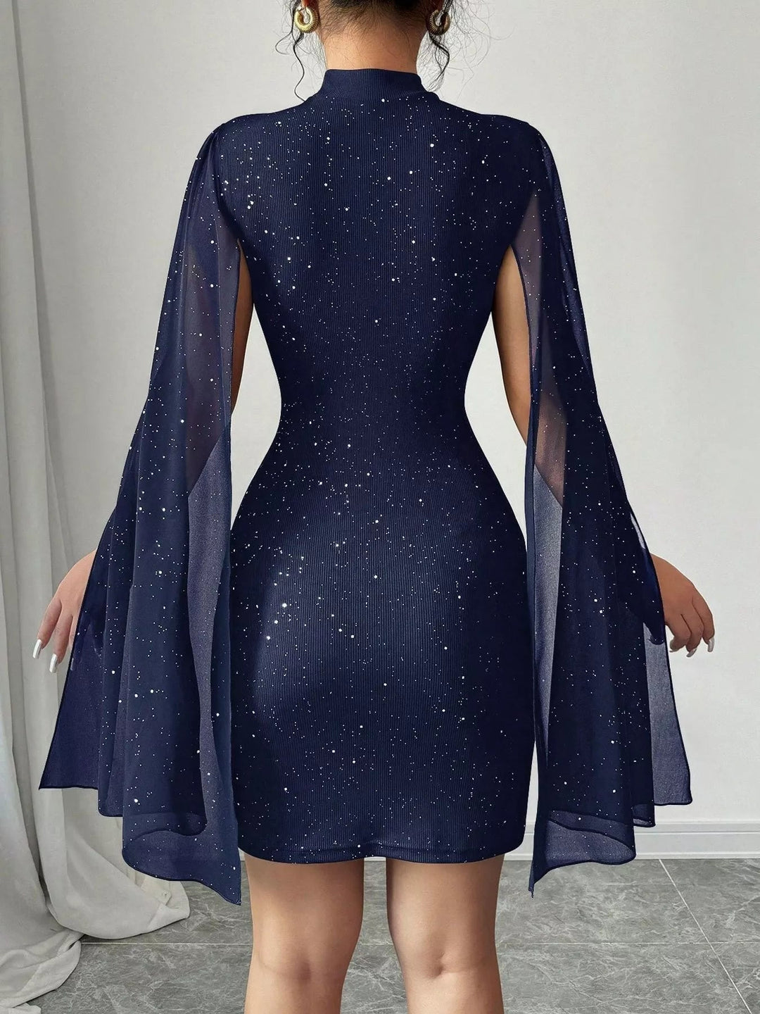 Glitter Cape Sleeve Mini Dress featuring shimmering fabric, elegant cape sleeves, subtle front cutout detail, and fitted bodycon mini silhouette.